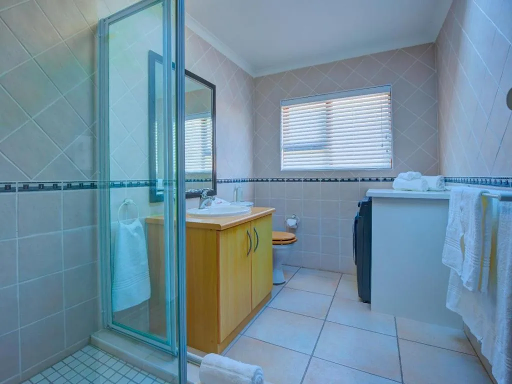 Spacious bathroom with shower enclosure, wooden vanity, and large mirror