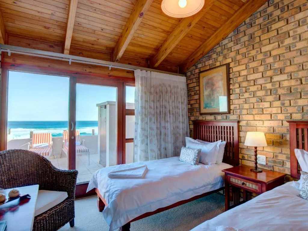 Bright bedroom with wooden beams, ocean view through glass doors to deck