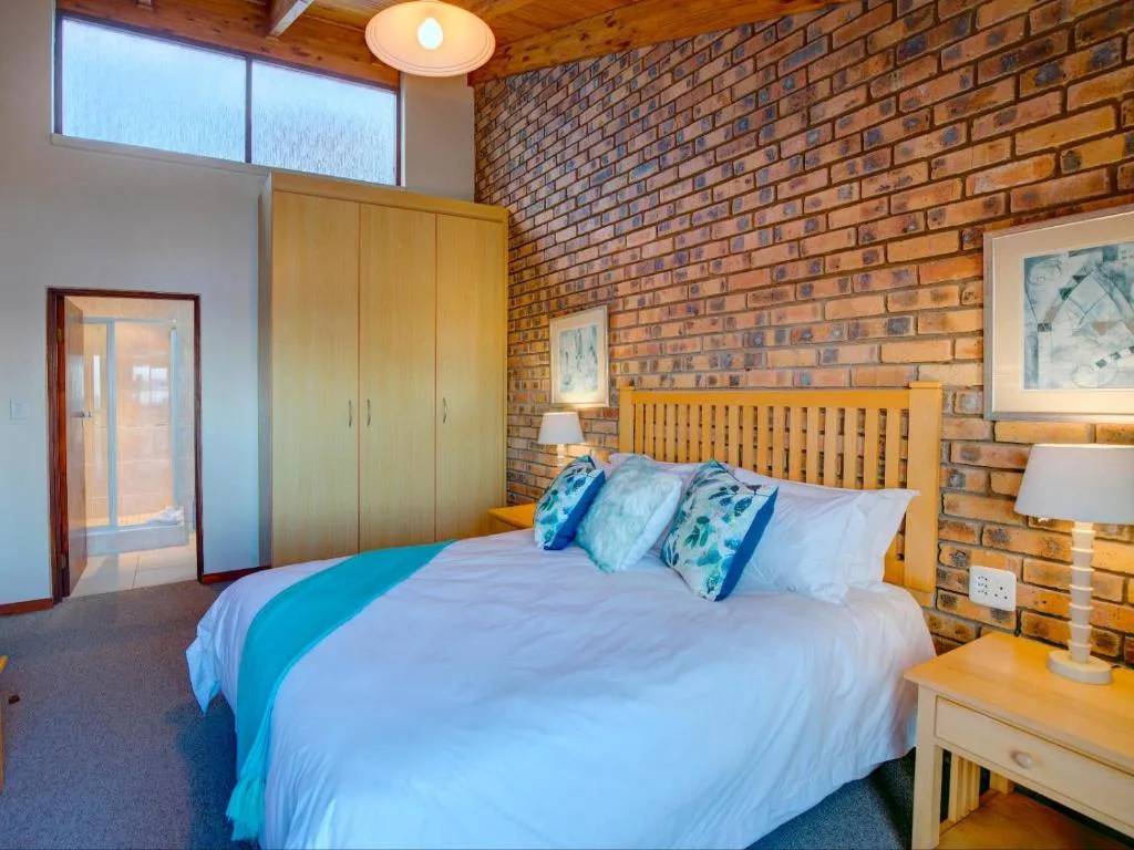 Spacious bedroom with wooden bed frame and exposed brick wall accent