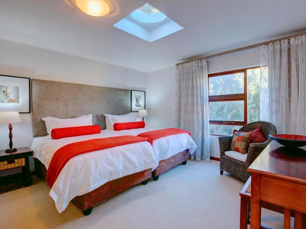 Bright bedroom with two beds, red throws, skylight, and mountain views