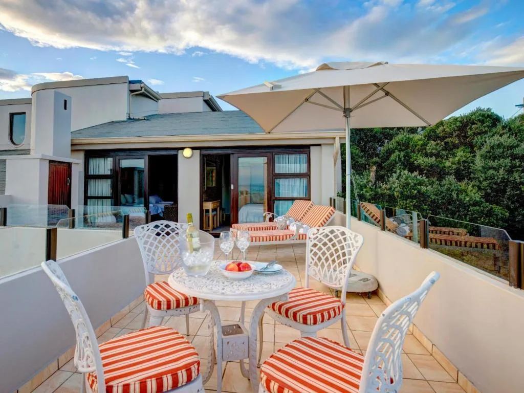 Spacious outdoor patio with dining table, white chairs, and large umbrella