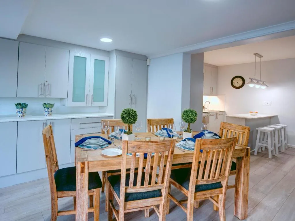 Modern dining area with wooden table, six chairs, and kitchen beyond