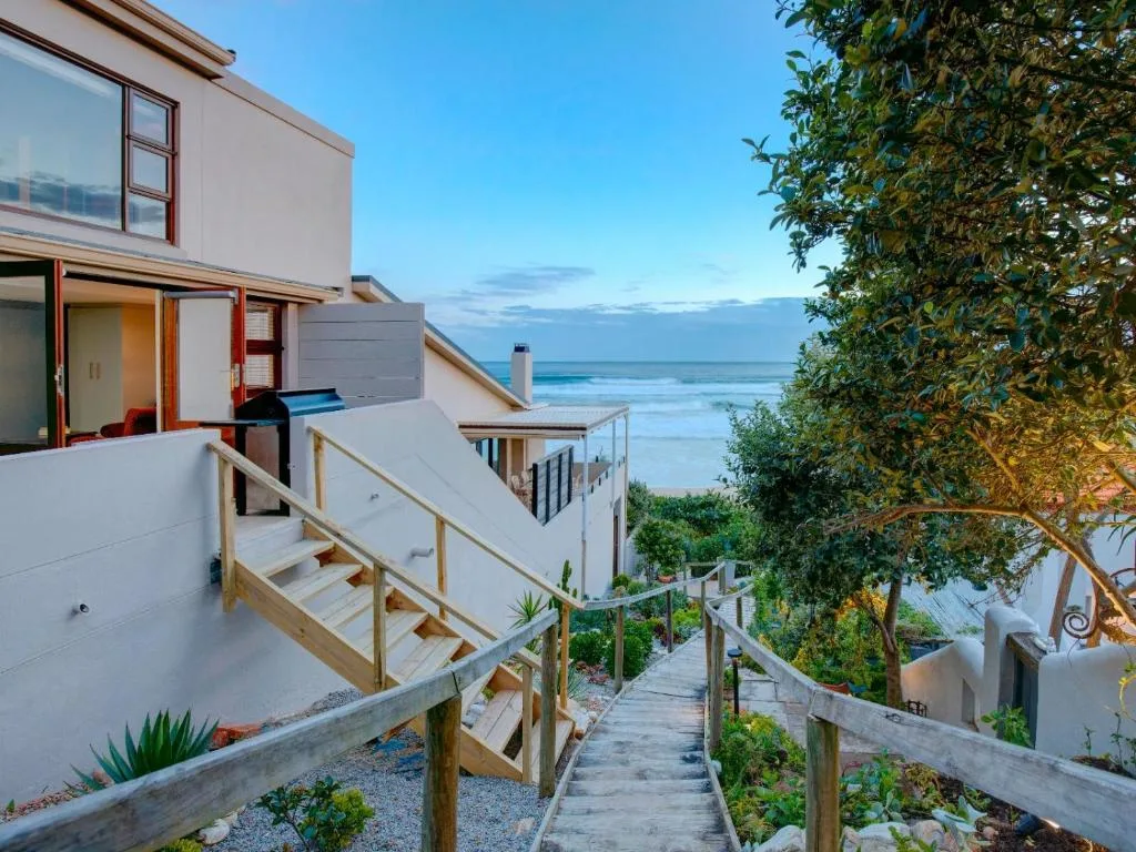 Modern beachfront property with wooden walkway and ocean view beyond