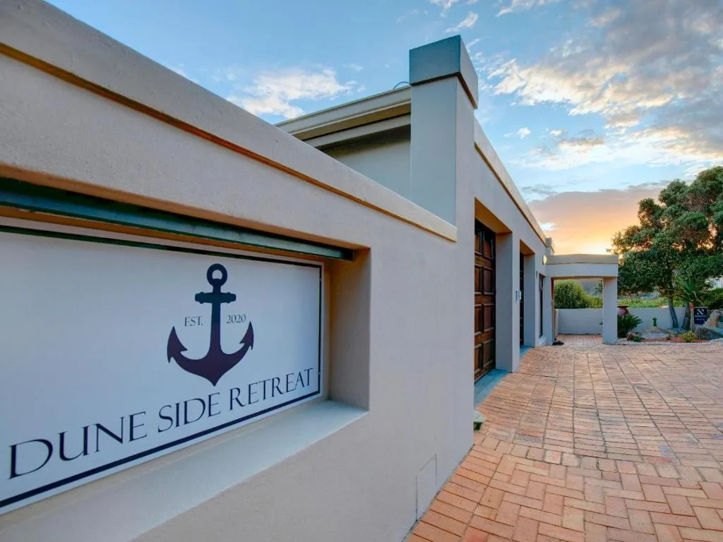 Modern white property facade with anchor logo signage and brick driveway