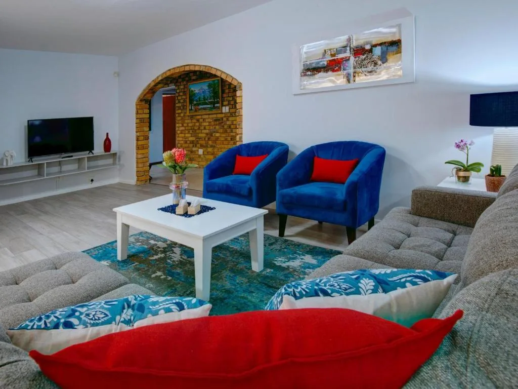 Spacious lounge with blue armchairs, gray sofas, white coffee table, and television