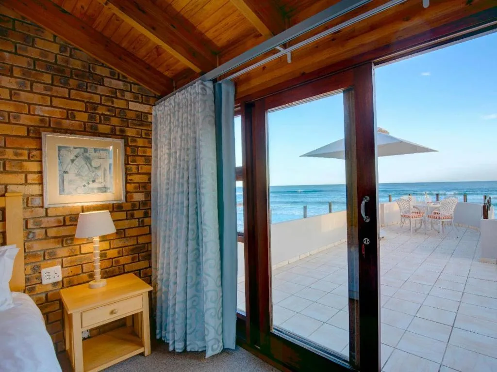 Ocean and beach view through open glass doors from beachfront accommodation