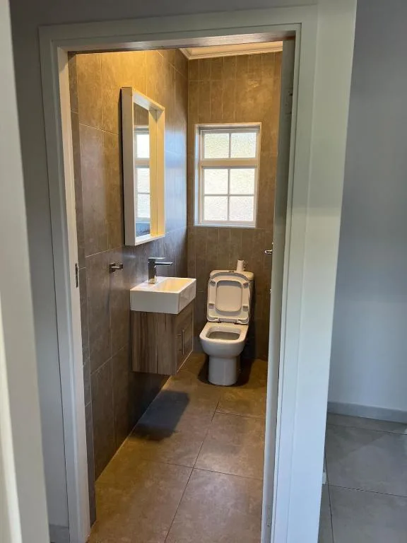 Modern bathroom with brown tile walls, white basin sink, and toilet