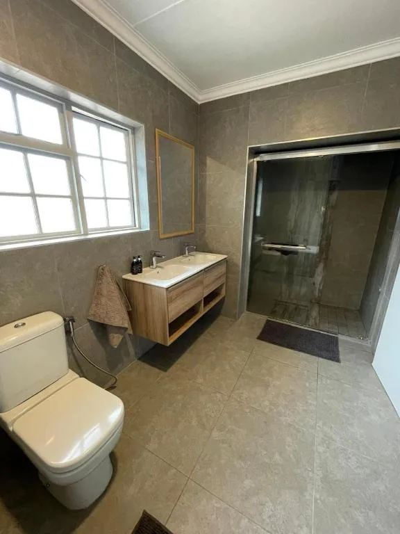 Modern bathroom with wooden vanity, walk-in shower, and toilet