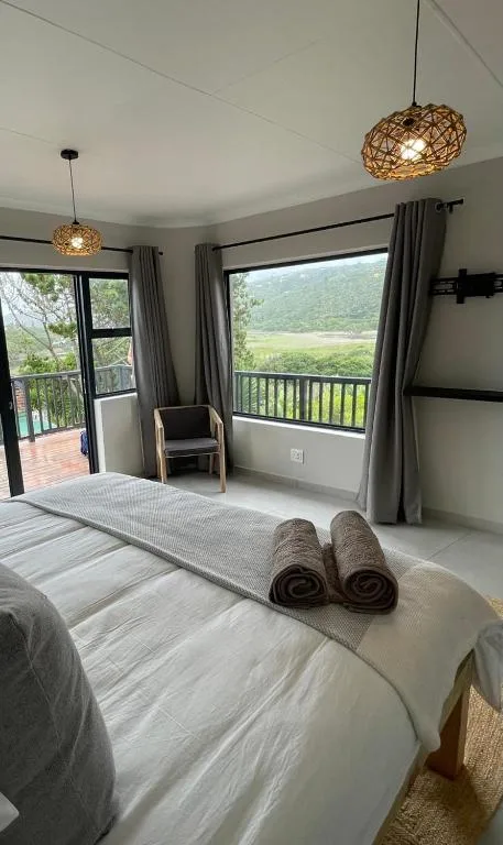 Bedroom with bed, scenic mountain valley view through large windows and doors