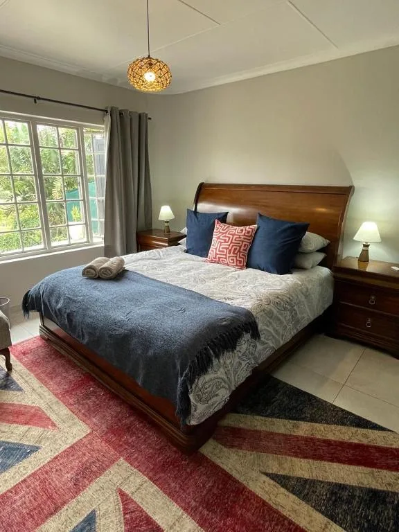 Spacious bedroom with wooden bed, blue bedding, decorative pillows, pendant light