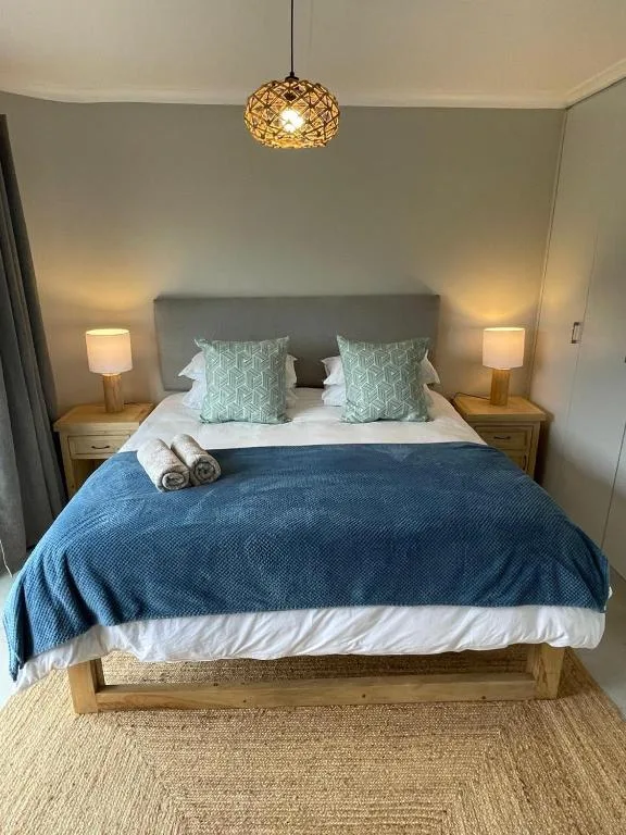 Master bedroom with queen bed, green cushions, wooden nightstands, pendant lighting