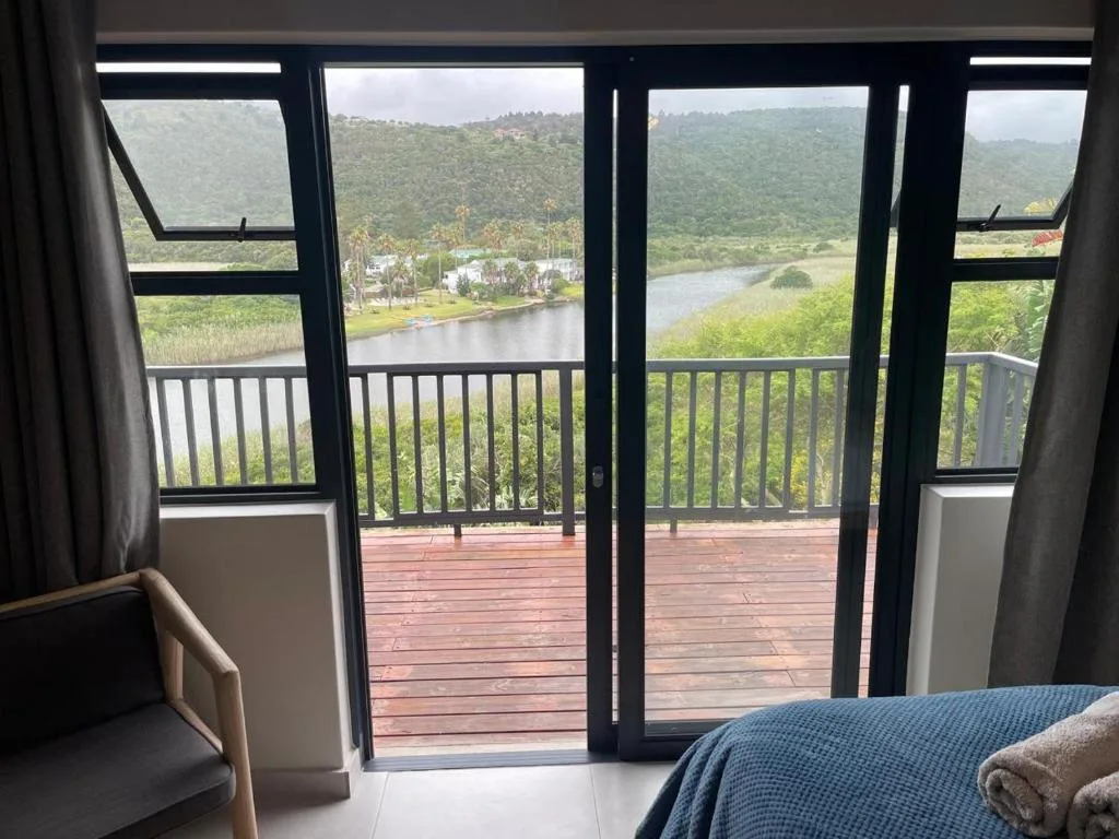 Bedroom with river and mountain views through glass doors to wooden deck