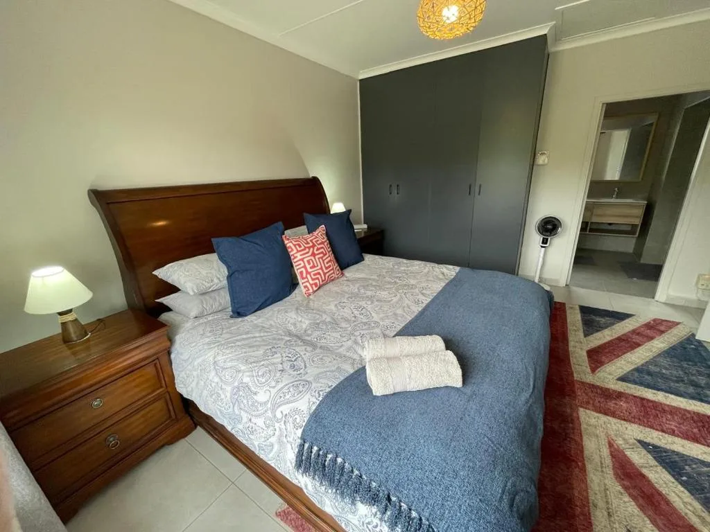 Spacious bedroom with wooden bed, blue bedding, and modern wardrobe
