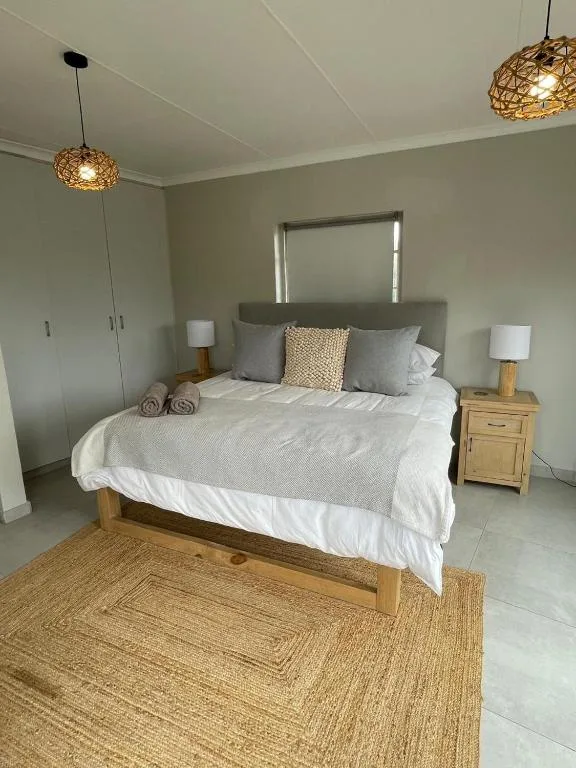 Spacious bedroom with wooden bed, gray headboard, woven pendant lights