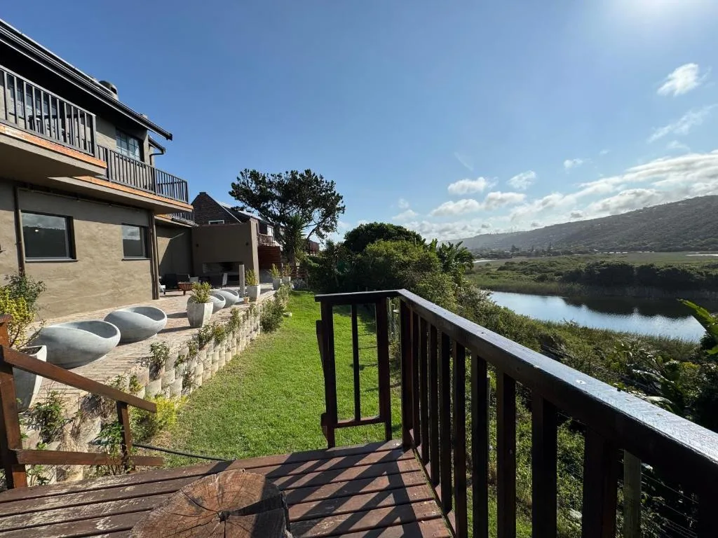 Wooden deck with railing overlooking manicured lawn and lagoon view