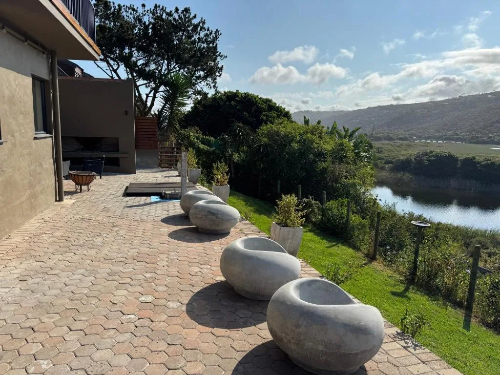 Paved patio with stone seating, lush gardens, and lagoon view beyond