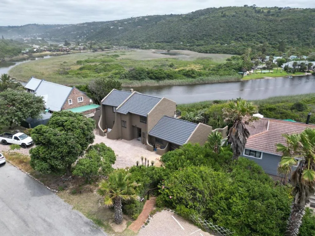 Modern house with solar panels overlooking lagoon and lush green hills