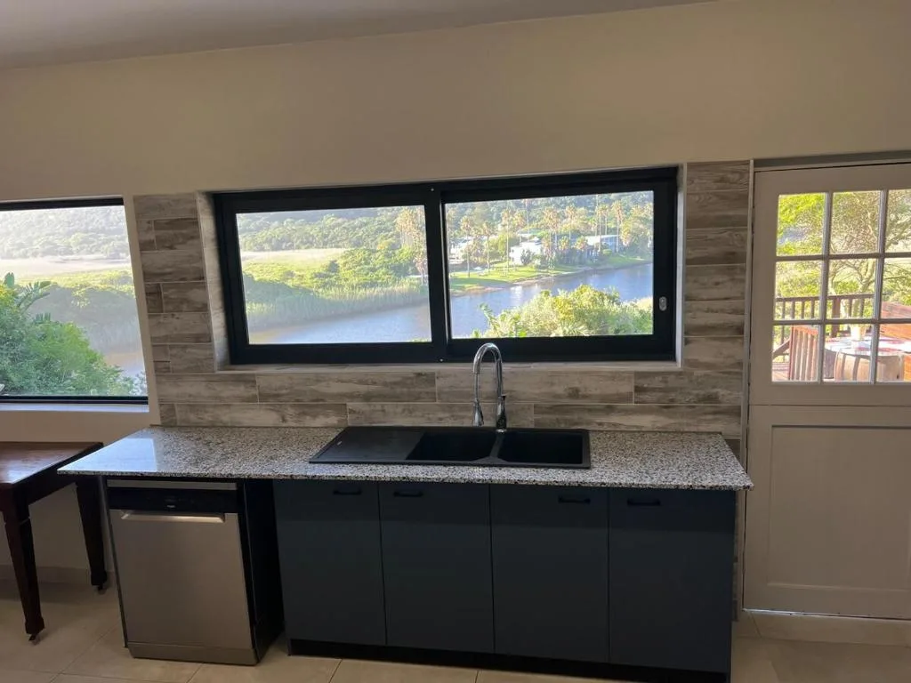 Modern kitchen with black cabinetry, granite countertop, and scenic lagoon views through windows