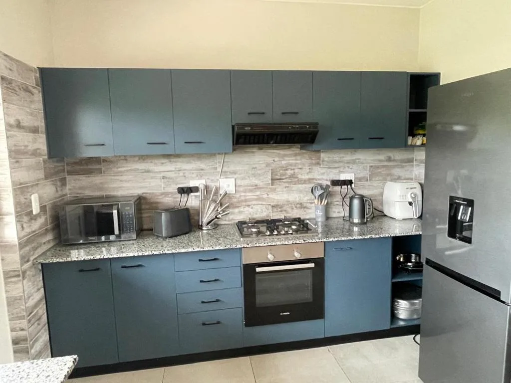 Modern kitchen with blue cabinetry, granite countertop, and stainless steel appliances