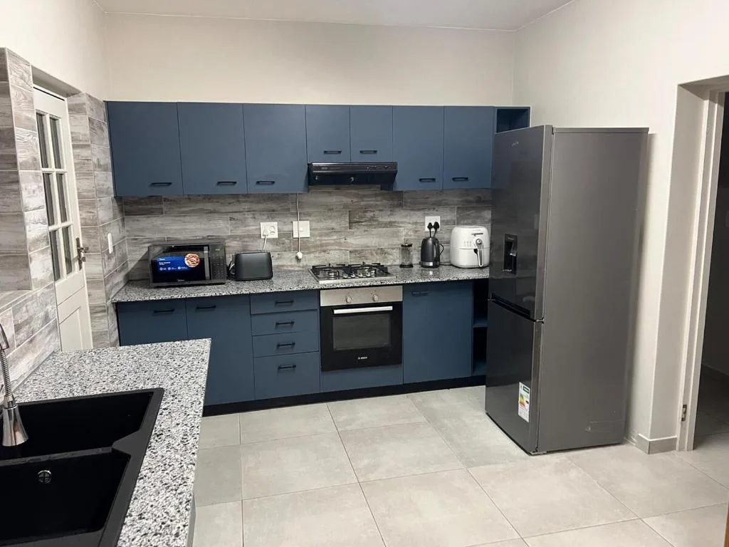 Modern kitchen with blue cabinetry, granite countertop, stainless steel appliances