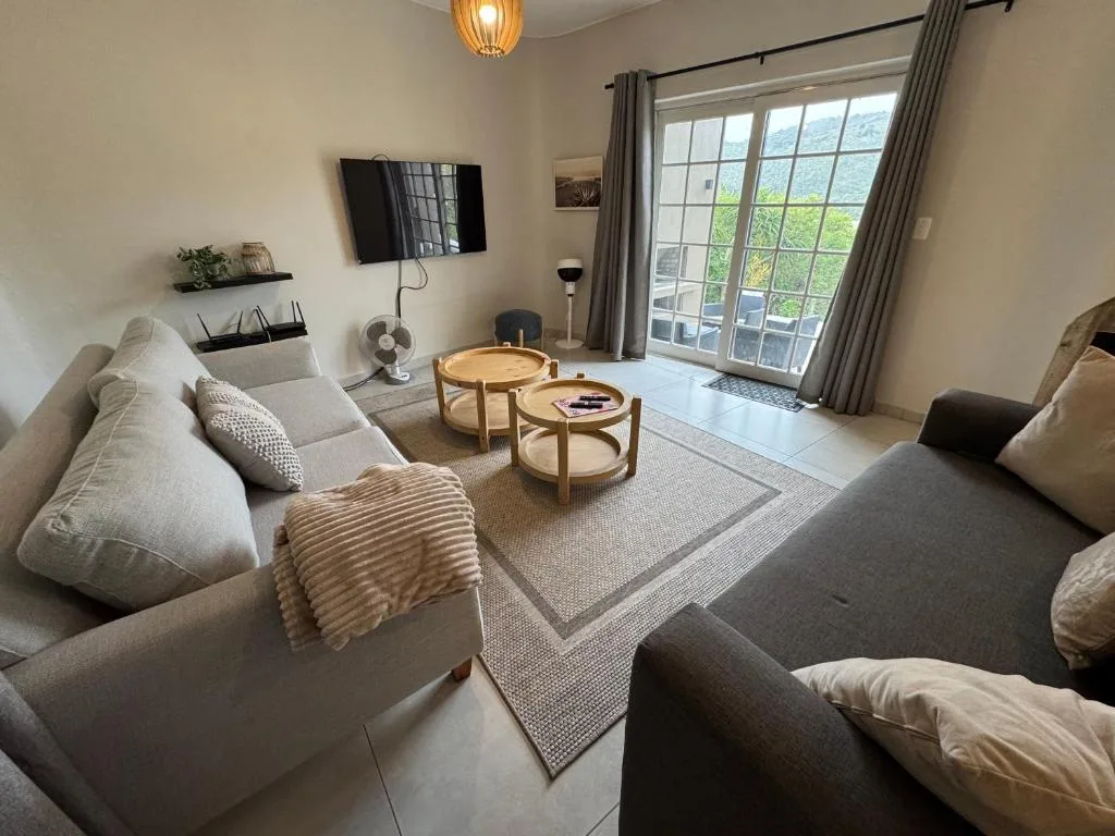 Bright lounge with comfortable sofas, wooden coffee tables, and large windows overlooking garden