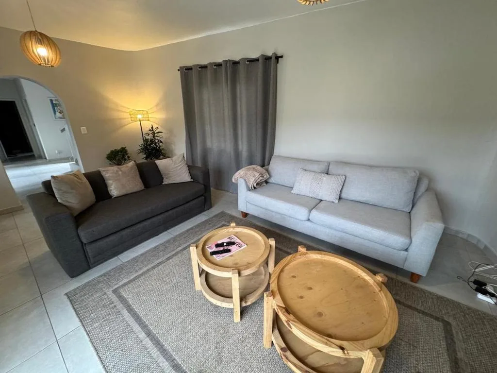 Spacious lounge with two sofas, round wooden tables, and warm lighting