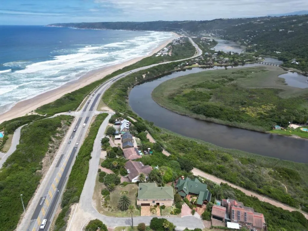 Aerial view of coastal property with lagoon, beach, and ocean horizon