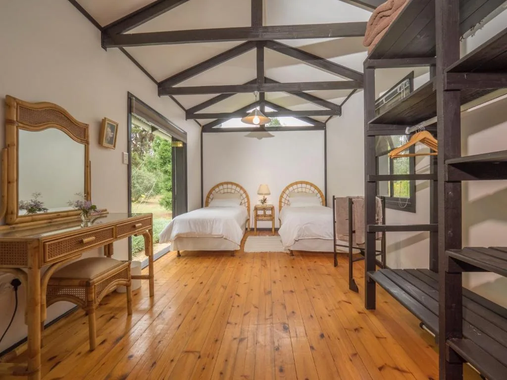 Spacious bedroom with two twin beds, wooden beams, and garden views