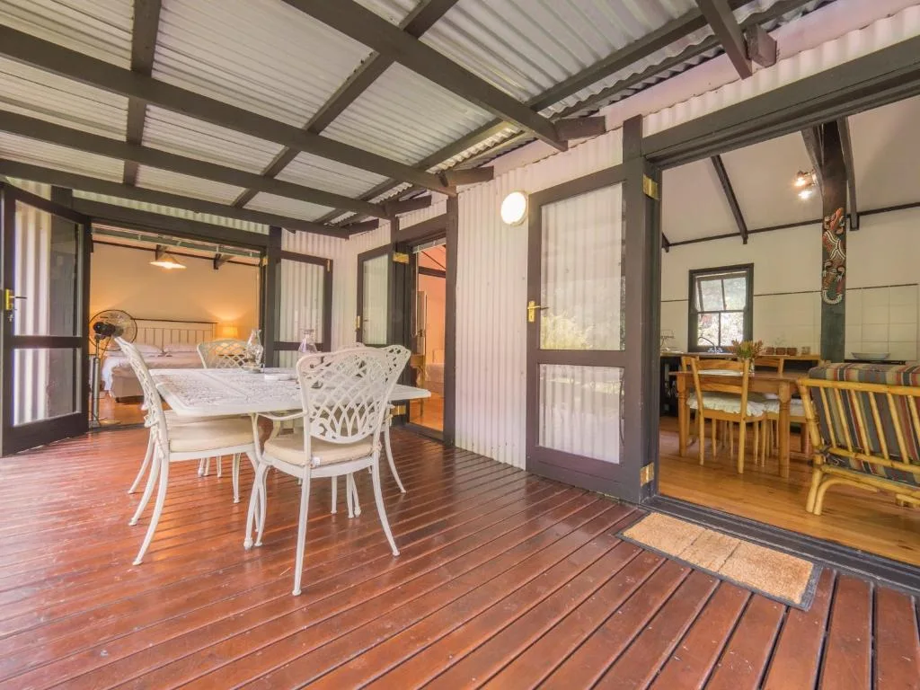 Open wooden deck with dining table overlooking bedroom and lounge areas