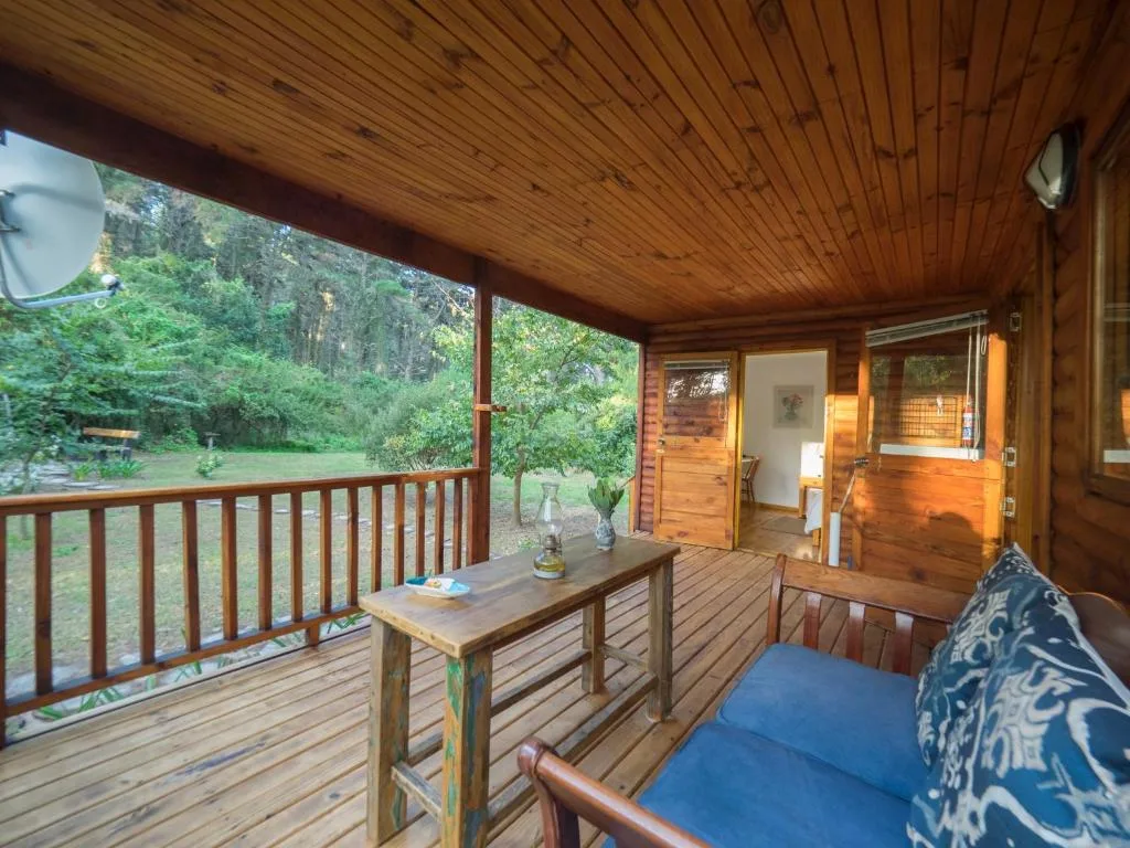 Covered wooden deck with table, seating, and forest views from cottage