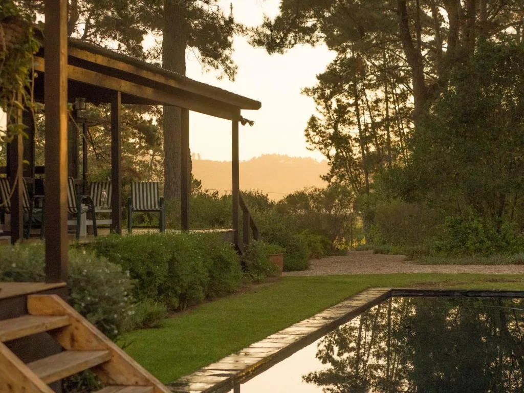 Wooden pergola and deck overlooking manicured garden and mountain views at sunset