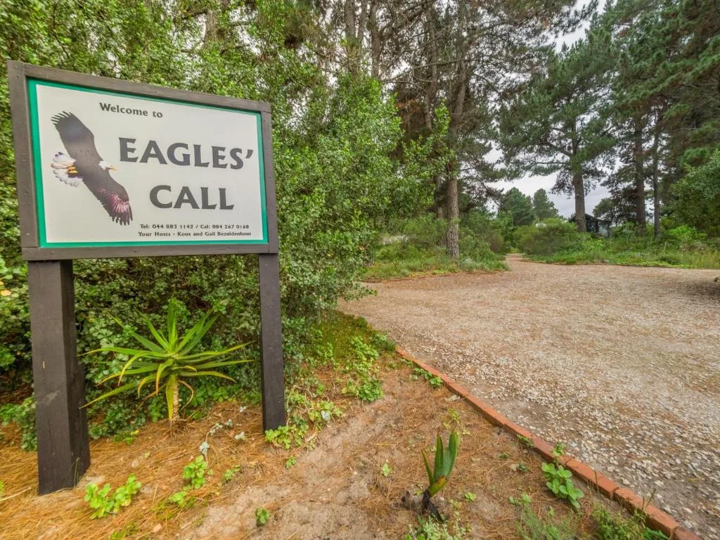 Welcome sign for Eagles' Call property surrounded by lush green trees and gravel driveway