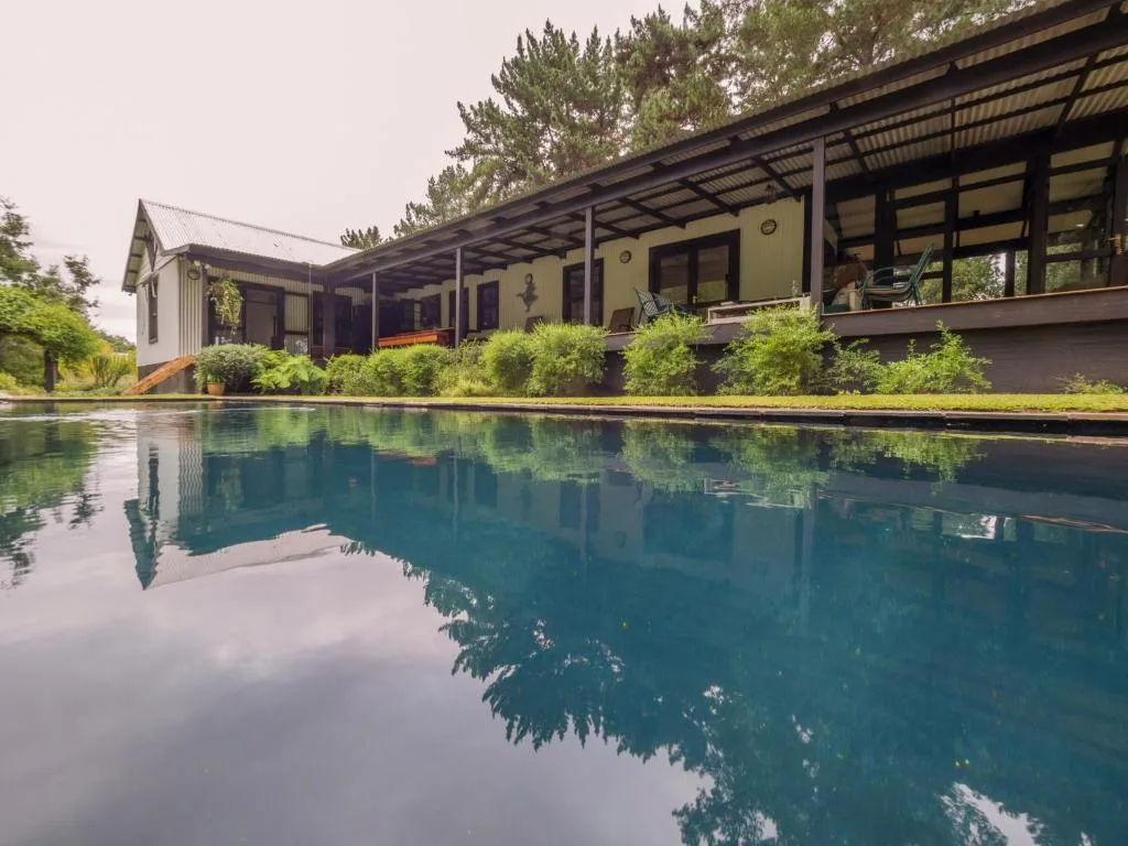 Sparkling blue swimming pool reflecting the modern cottage and surrounding greenery