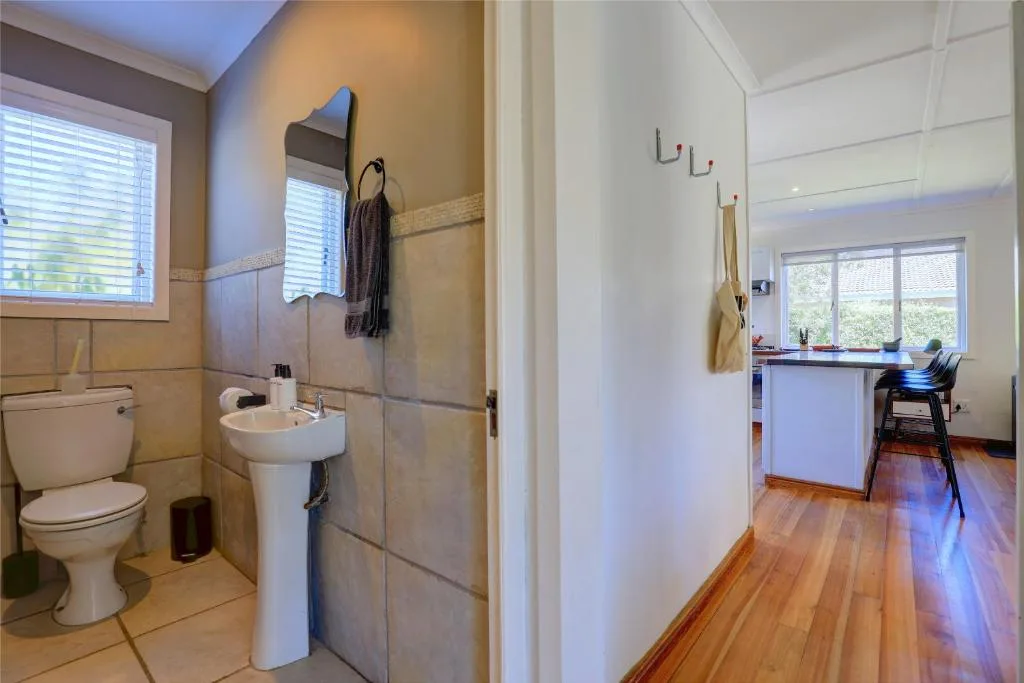 Modern bathroom with toilet, pedestal sink, and tiled shower area
