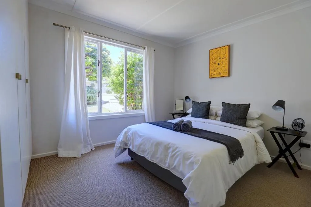 Bright bedroom with queen bed, large windows overlooking garden, modern decor