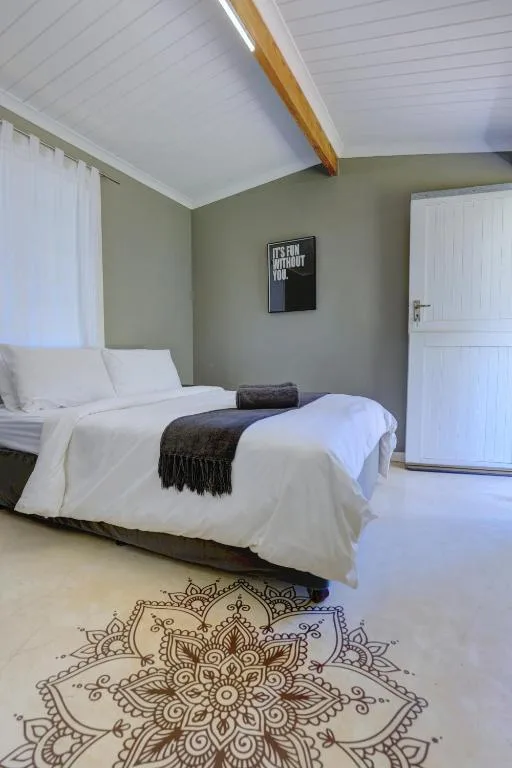 Bright bedroom with white bedding, sage green walls, wooden beam ceiling