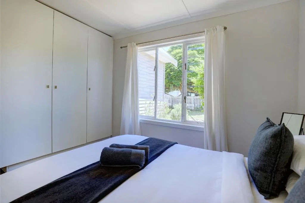Bright bedroom with white bed, built-in wardrobes, and garden views