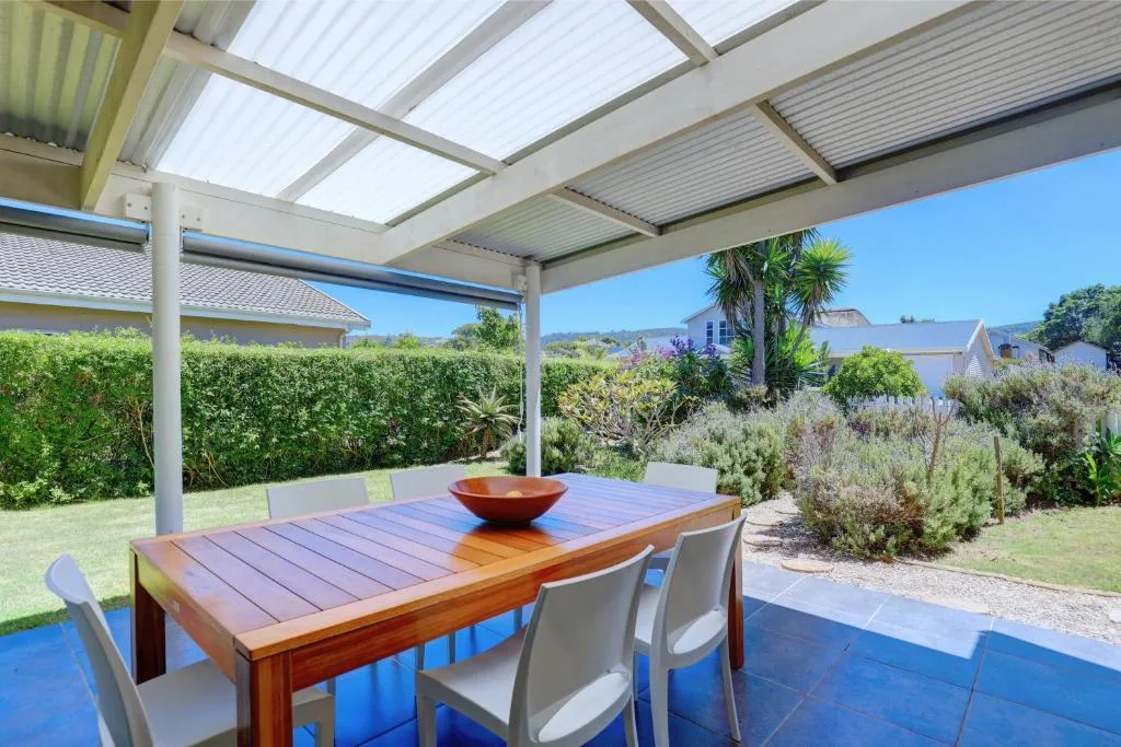 Covered patio with wooden dining table overlooking garden and mountains