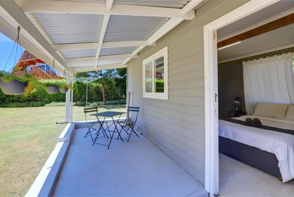 Covered patio with dining table, chairs, and garden views beyond
