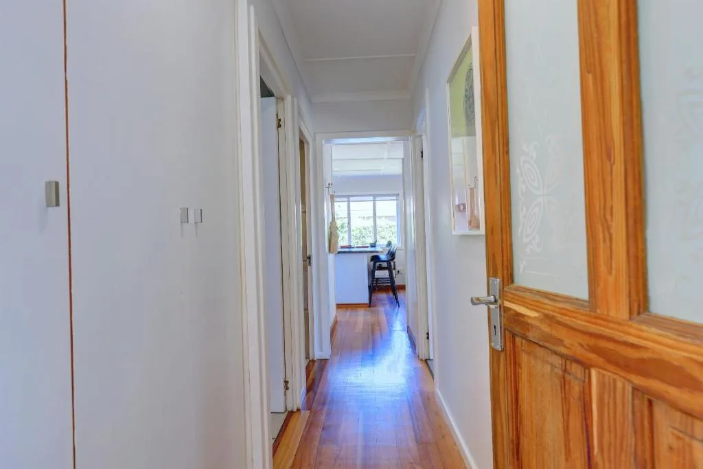 Bright hallway with wooden doors and polished floors leading to windows