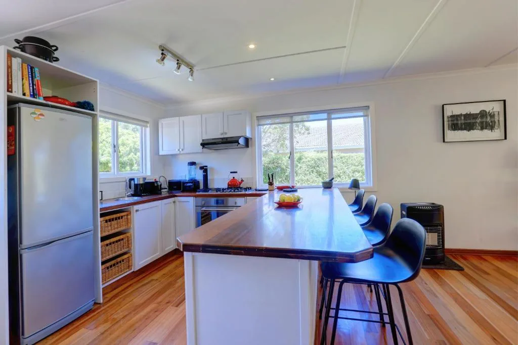 Modern kitchen with white cabinetry, island seating, and large windows overlooking garden