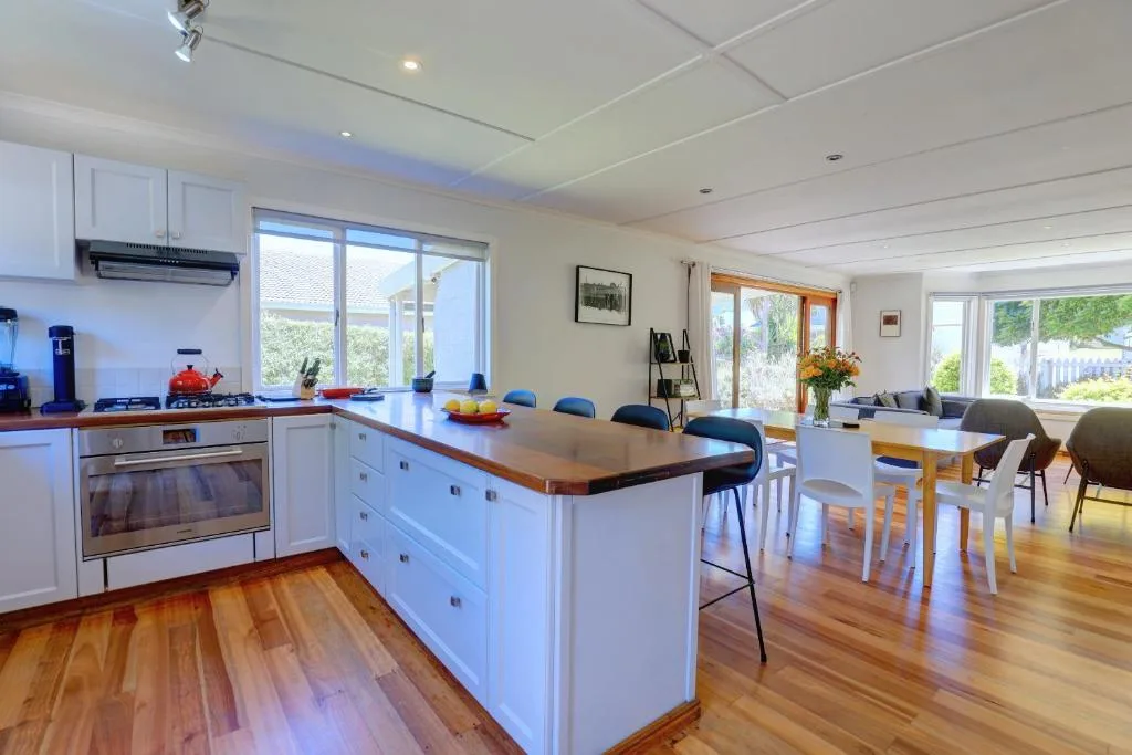 Modern kitchen with white cabinetry, wood countertop island, and stainless steel appliances