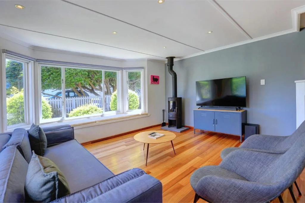 Spacious living room with blue sofas, flat-screen TV, and garden views