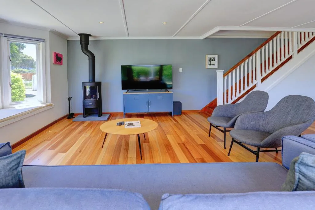 Open-plan lounge with TV, wood stove, and comfortable seating areas