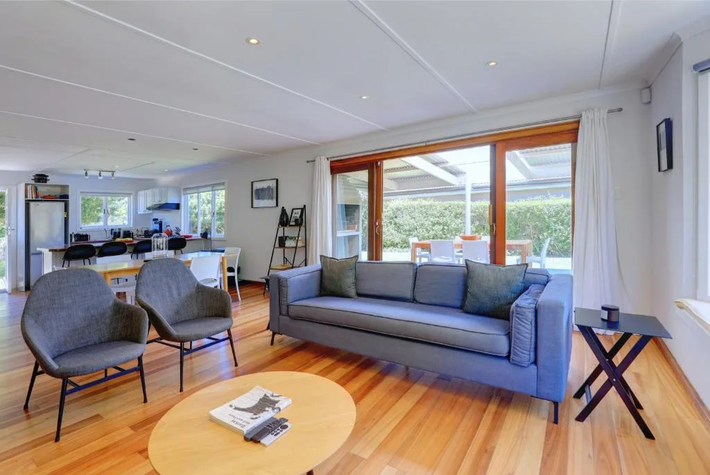 Modern lounge with gray sofa, armchairs, and wooden coffee table overlooking garden
