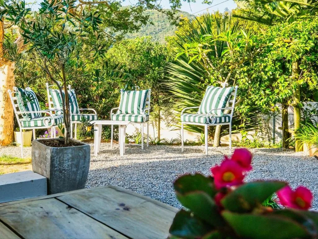Striped lounge chairs and side table on gravel patio with lush garden surroundings