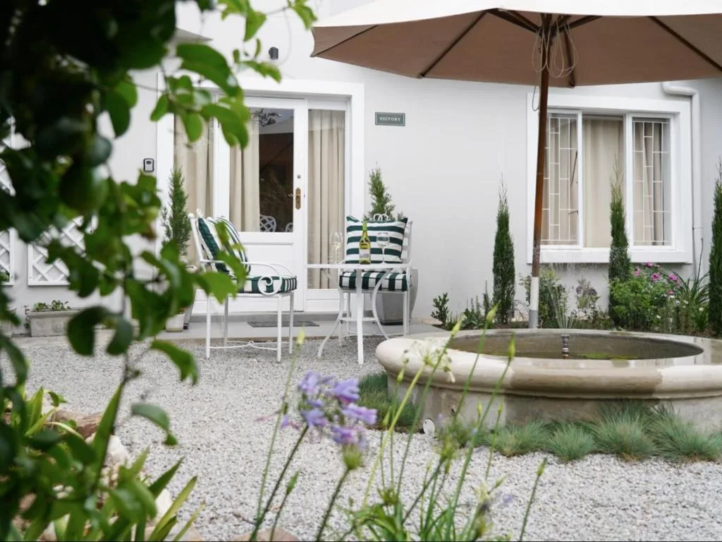 Shaded patio with seating, umbrella, and garden water feature