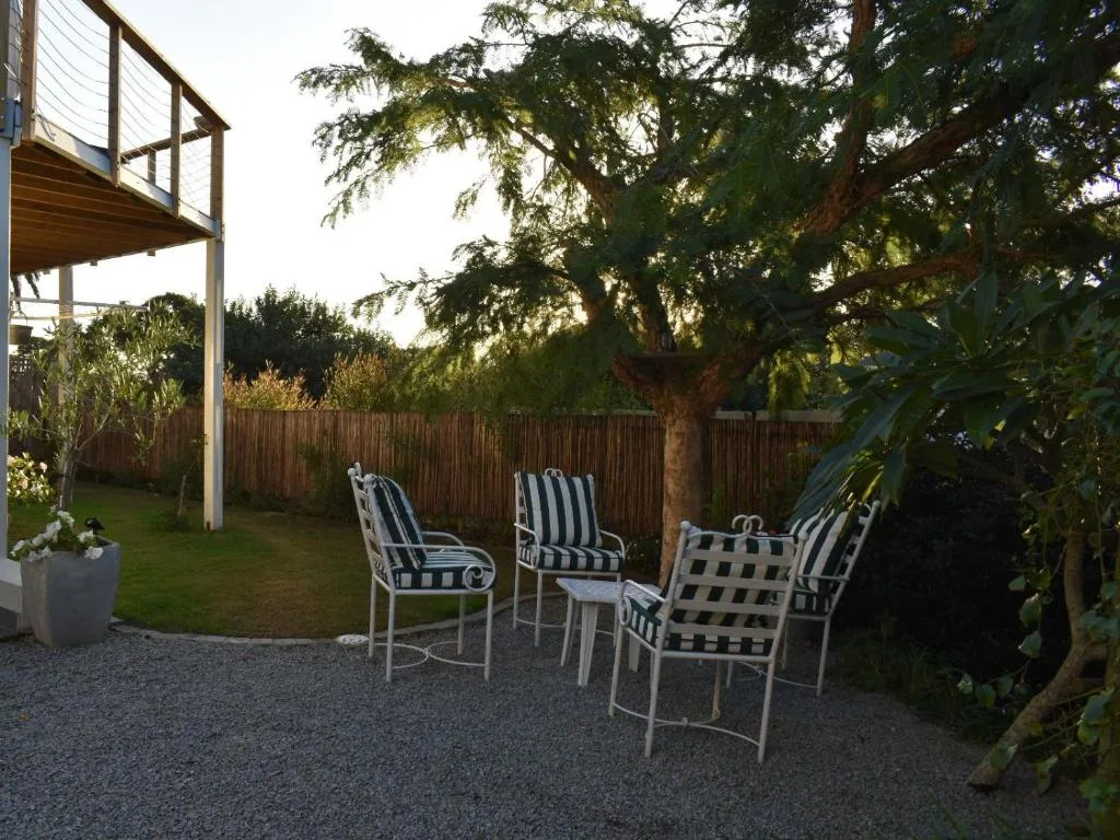 Outdoor seating area with striped chairs under mature trees and shade structure