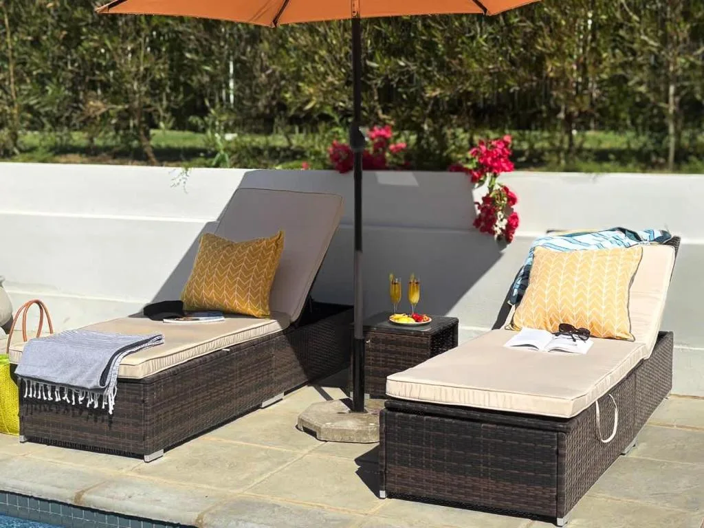 Shaded poolside loungers with cushions and umbrellas overlooking gardens