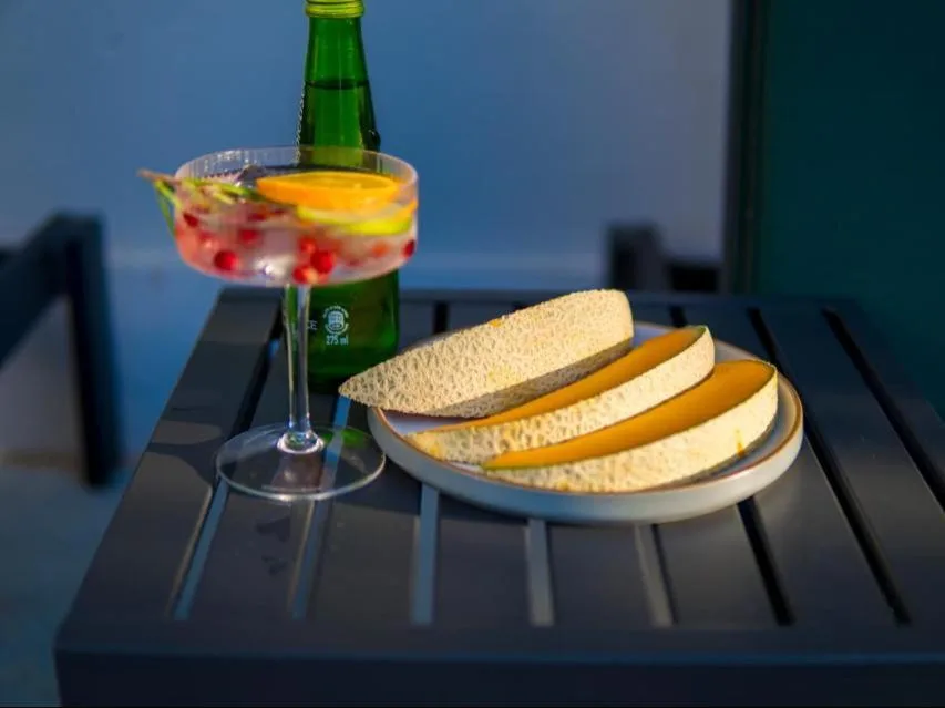 Cocktail and snacks on outdoor table at dusk, ocean view background